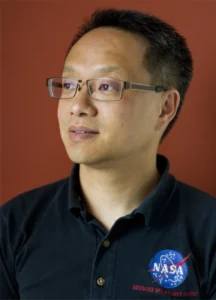 This photo is a headshot of Eric Choi in profile wearing a black polo shirt with NASA logo just visible on the left front of the shirt. Photo credit Jim Hines. 